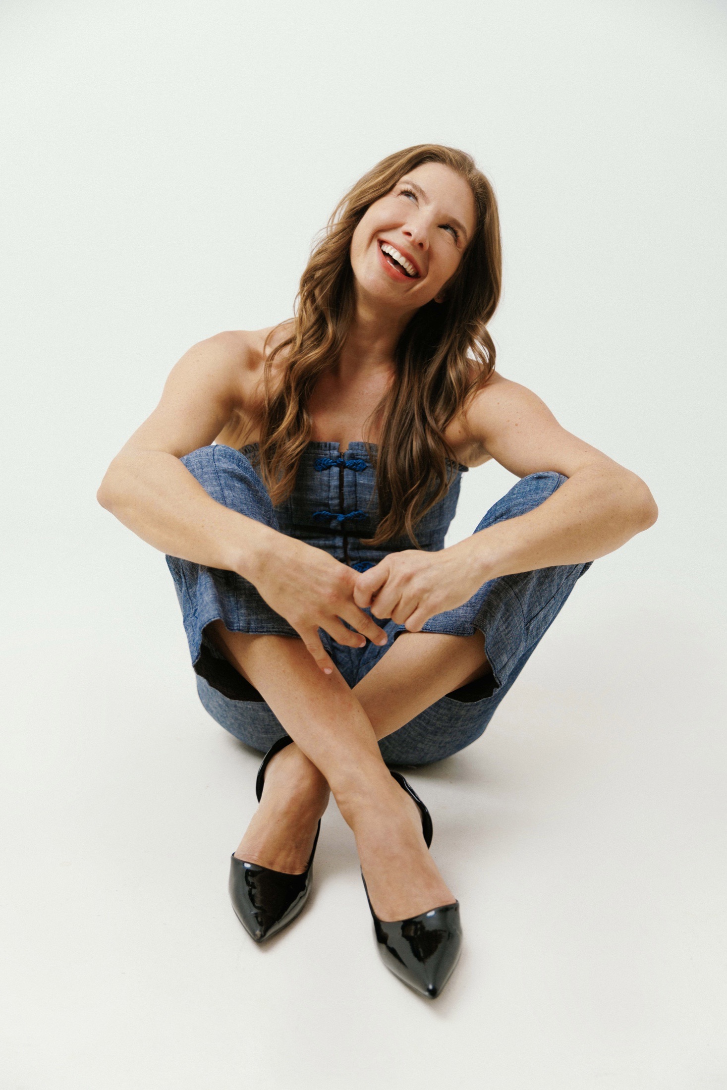 Dani Faitelson smiling in a jean outfit while seated on the floor